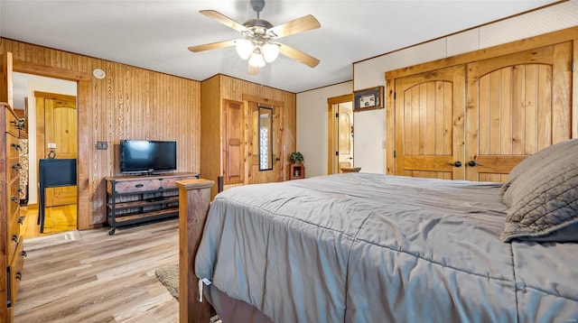 bedroom with ceiling fan, light hardwood / wood-style flooring, and wood walls