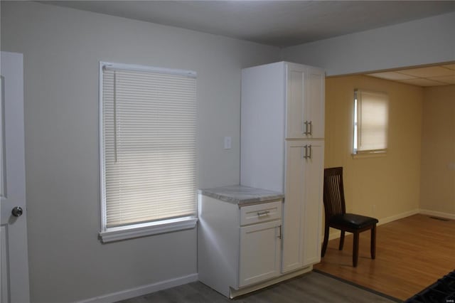 interior space featuring dark wood-style flooring, white cabinets, and baseboards