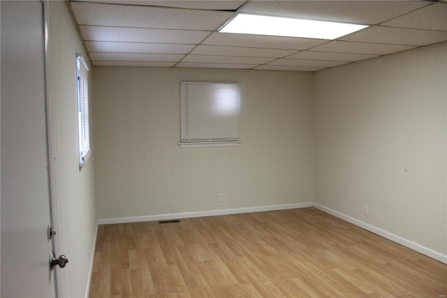 spare room with light wood-type flooring, baseboards, visible vents, and a paneled ceiling