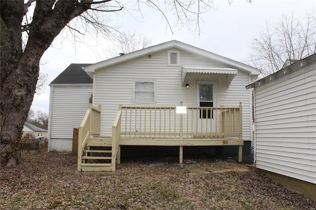 back of house with roof with shingles and a deck