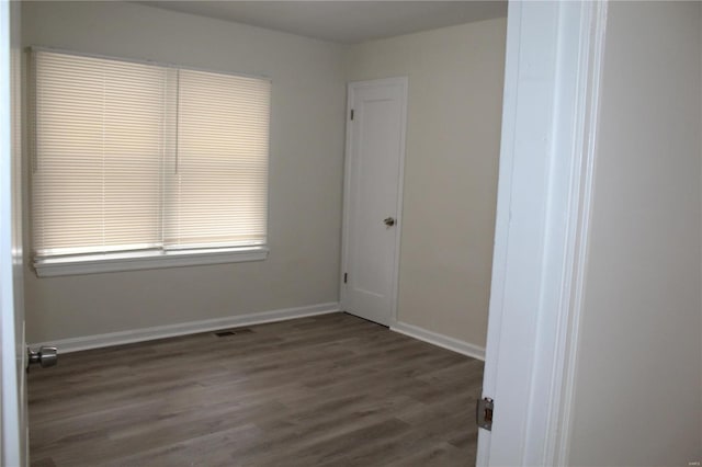 spare room featuring visible vents, baseboards, and wood finished floors