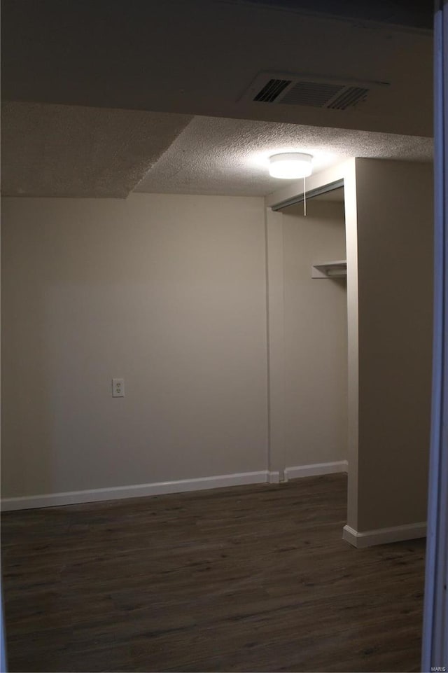 interior space with dark wood-style floors, visible vents, a textured ceiling, and baseboards