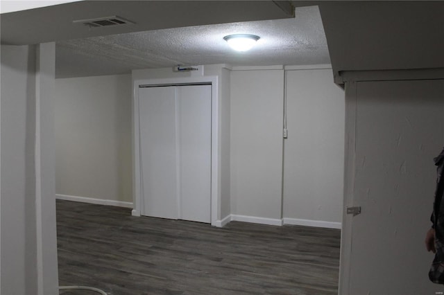 basement featuring dark hardwood / wood-style floors and a textured ceiling