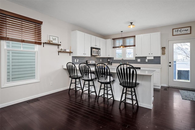 kitchen with white cabinetry, a breakfast bar area, pendant lighting, and kitchen peninsula