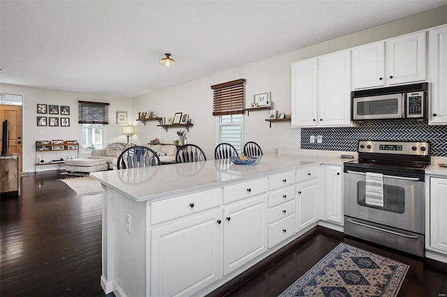 kitchen with white cabinetry, appliances with stainless steel finishes, kitchen peninsula, and plenty of natural light