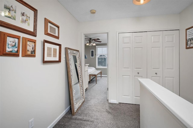 corridor with a textured ceiling and dark colored carpet