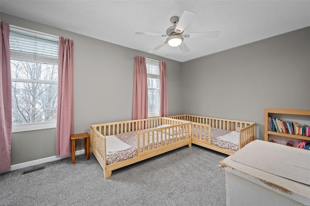 carpeted bedroom with ceiling fan and a textured ceiling