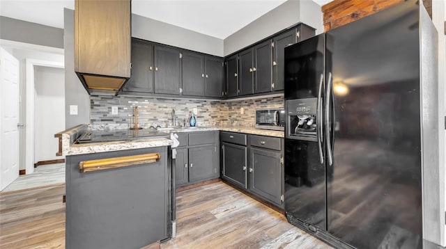 kitchen with sink, gray cabinets, tasteful backsplash, light hardwood / wood-style floors, and black fridge