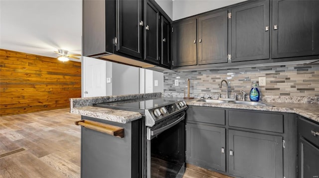 kitchen featuring decorative backsplash, sink, stainless steel range with electric cooktop, and light hardwood / wood-style flooring