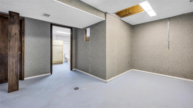 basement featuring white refrigerator and a drop ceiling