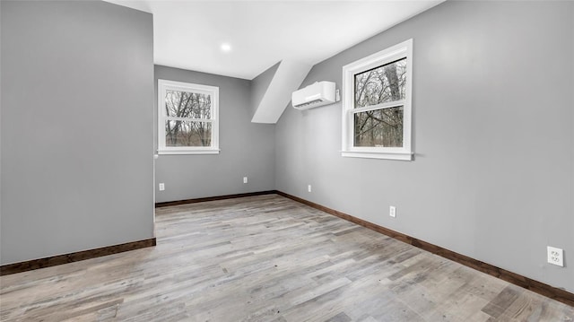 spare room featuring an AC wall unit and light hardwood / wood-style flooring