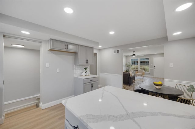 kitchen with visible vents, light wood-style flooring, light stone counters, gray cabinets, and recessed lighting