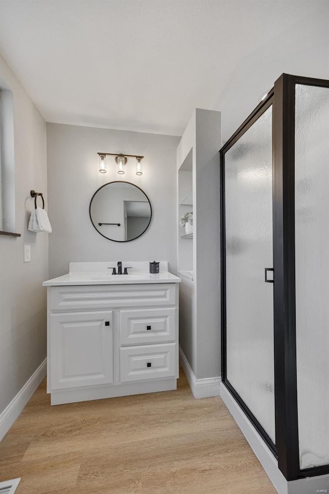 full bath featuring a stall shower, baseboards, wood finished floors, and vanity