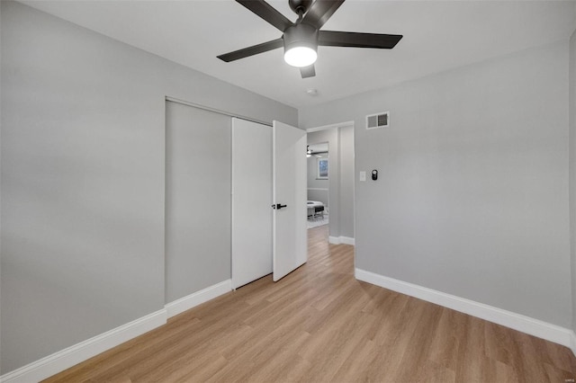 unfurnished bedroom with ceiling fan, light wood-style flooring, visible vents, baseboards, and a closet