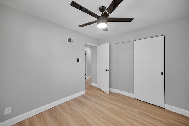 unfurnished bedroom featuring a closet, visible vents, baseboards, and wood finished floors