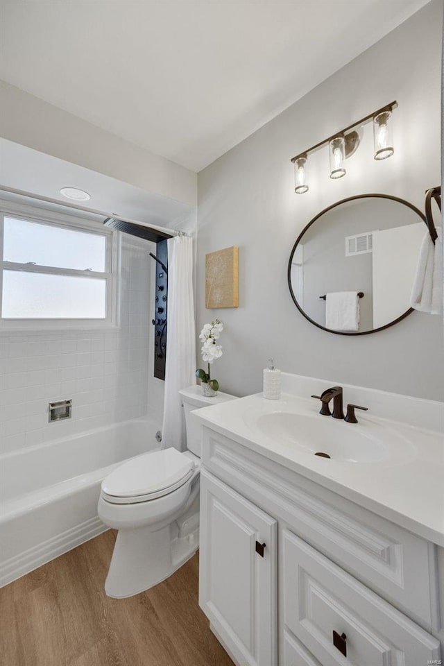 full bath with toilet, wood finished floors, visible vents, vanity, and shower / bath combo