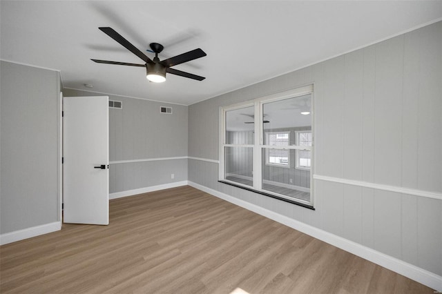 empty room featuring baseboards, visible vents, and wood finished floors