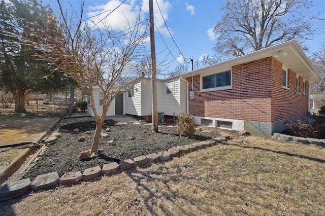 view of property exterior featuring central AC unit, fence, and brick siding