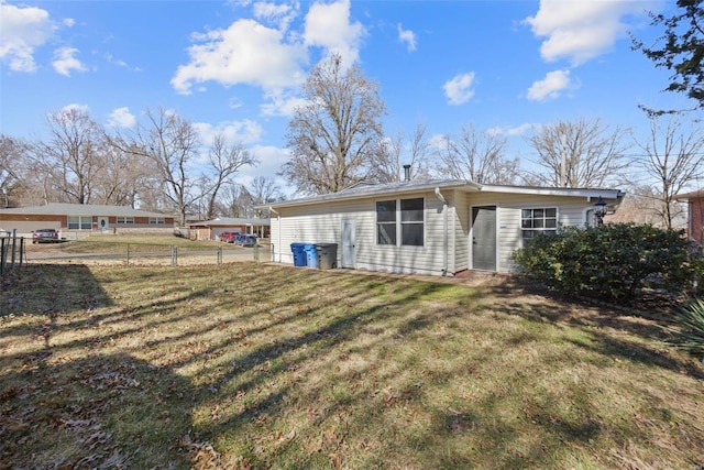 rear view of property featuring fence and a lawn