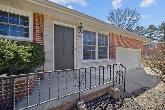 doorway to property with concrete driveway, brick siding, and an attached garage