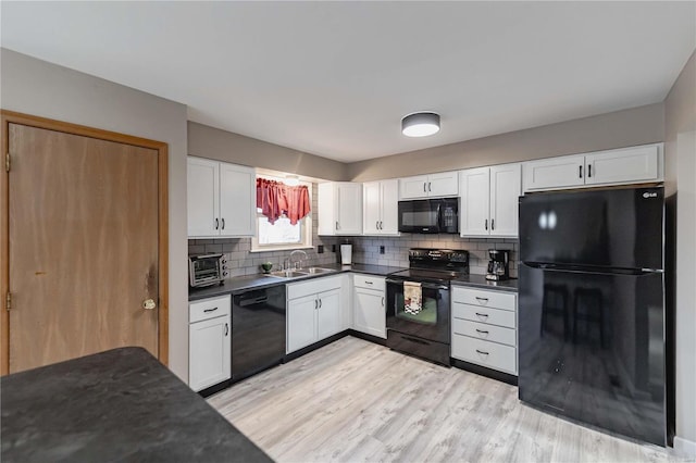 kitchen with white cabinetry, sink, decorative backsplash, and black appliances