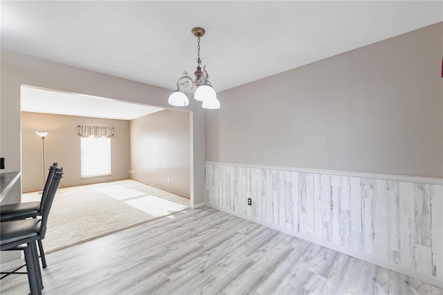 unfurnished dining area with light hardwood / wood-style flooring and a notable chandelier