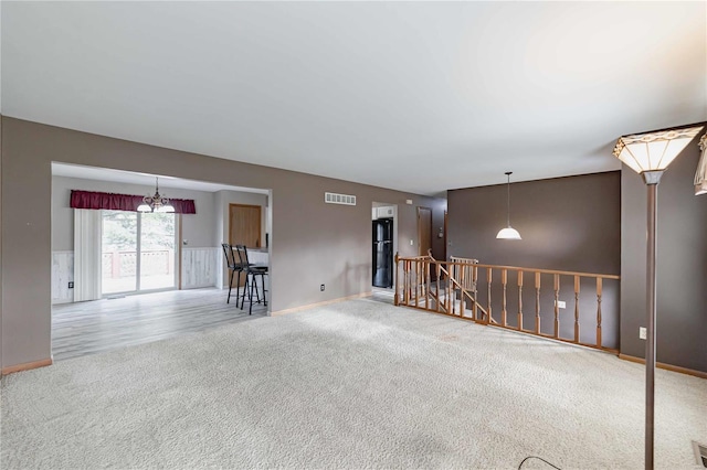 carpeted empty room featuring a chandelier