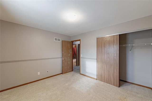 unfurnished bedroom with light carpet and a closet