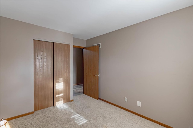 unfurnished bedroom with light colored carpet and a closet