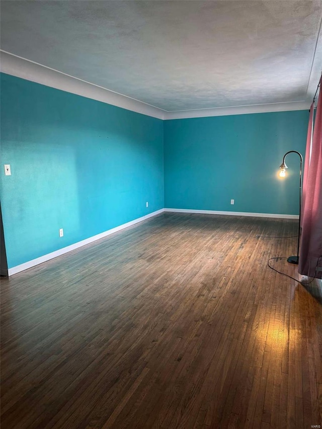 empty room with crown molding and dark hardwood / wood-style floors