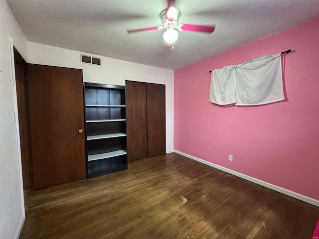 unfurnished bedroom featuring dark hardwood / wood-style flooring, ceiling fan, a closet, and a textured ceiling