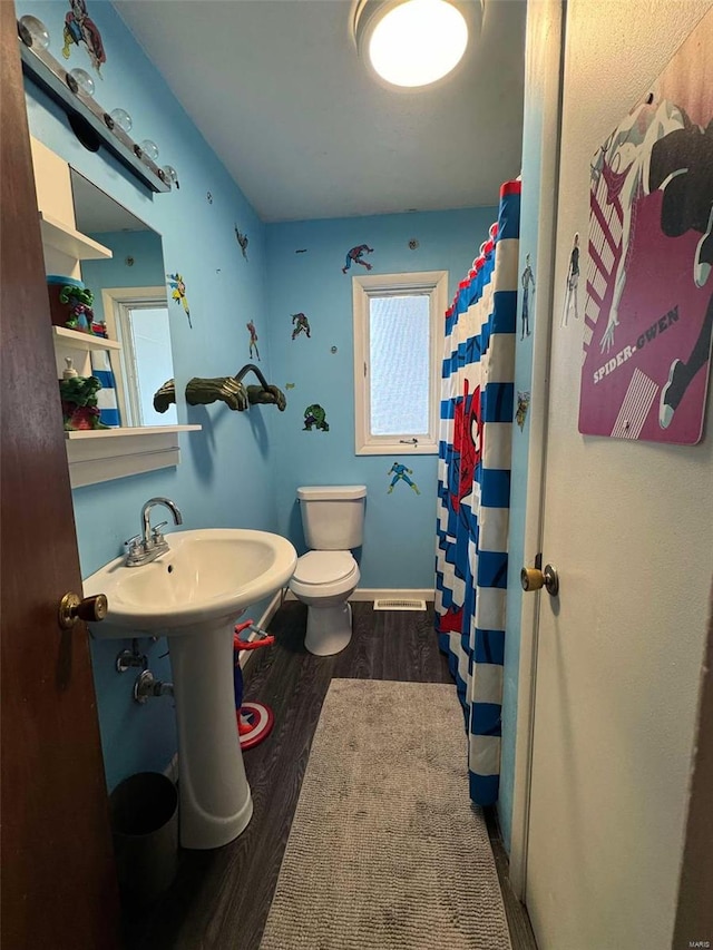 bathroom with hardwood / wood-style flooring, a wealth of natural light, curtained shower, and toilet