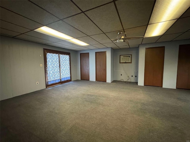 empty room with a drop ceiling, an AC wall unit, and carpet