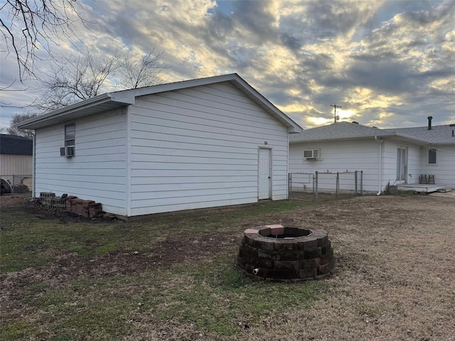 property exterior at dusk with a lawn and a fire pit