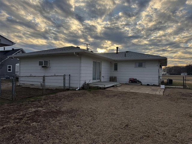 back house at dusk featuring central air condition unit, a patio, and an AC wall unit