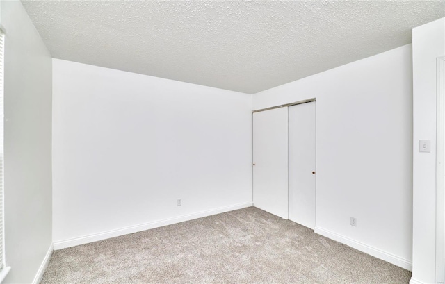 unfurnished bedroom featuring light carpet, a closet, and a textured ceiling