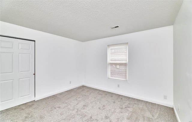 carpeted spare room featuring a textured ceiling