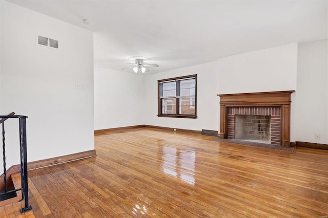 unfurnished living room with a fireplace, ceiling fan, and light wood-type flooring