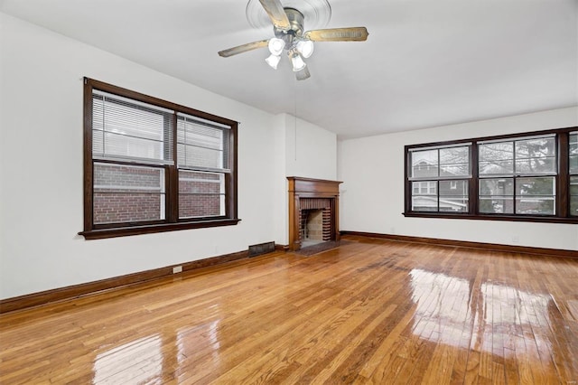 unfurnished living room with ceiling fan, a fireplace, and light hardwood / wood-style flooring