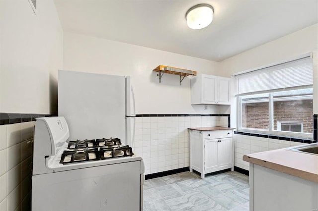 kitchen with white cabinetry, tile walls, and white appliances