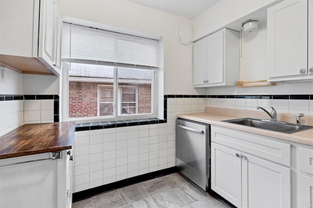 kitchen with tile walls, white cabinets, sink, and dishwasher