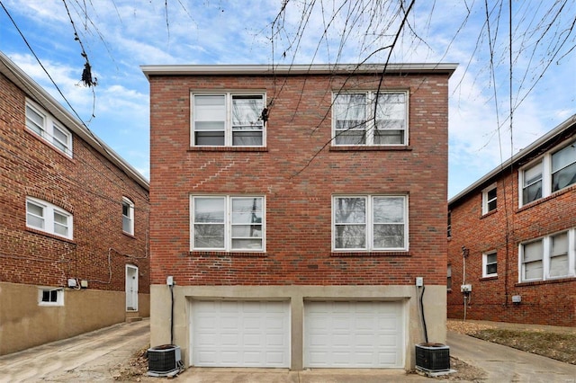 rear view of property featuring a garage and central AC