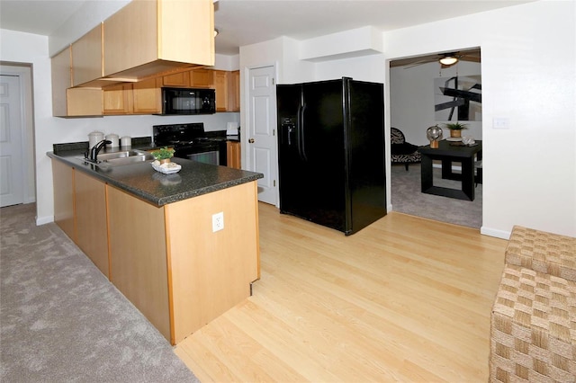 kitchen with sink, black appliances, kitchen peninsula, and light wood-type flooring