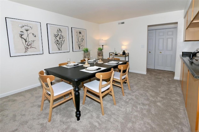 dining area featuring sink and light carpet