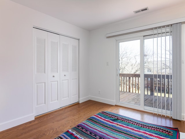 bedroom featuring access to exterior, wood-type flooring, and a closet