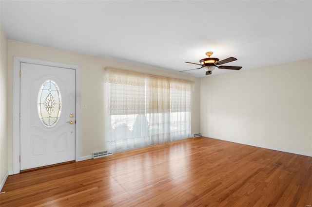 foyer entrance with visible vents, baseboards, wood finished floors, and a ceiling fan