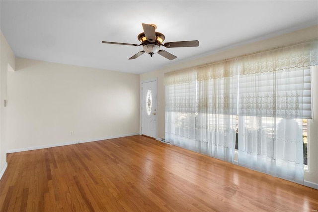 empty room with a healthy amount of sunlight, baseboards, a ceiling fan, and wood finished floors