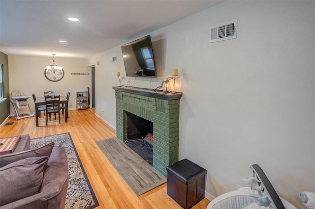 living room featuring a brick fireplace, hardwood / wood-style floors, and an inviting chandelier