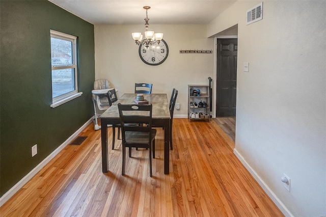 dining room with light hardwood / wood-style flooring and a notable chandelier