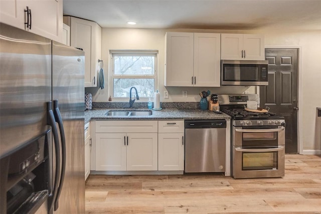 kitchen featuring white cabinetry, appliances with stainless steel finishes, sink, and light hardwood / wood-style flooring